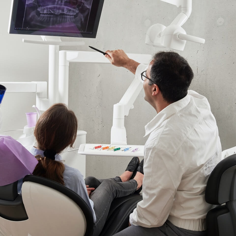 A dentist looking over a xray with a patient photo by Photo by Caroline LM via Unsplash
